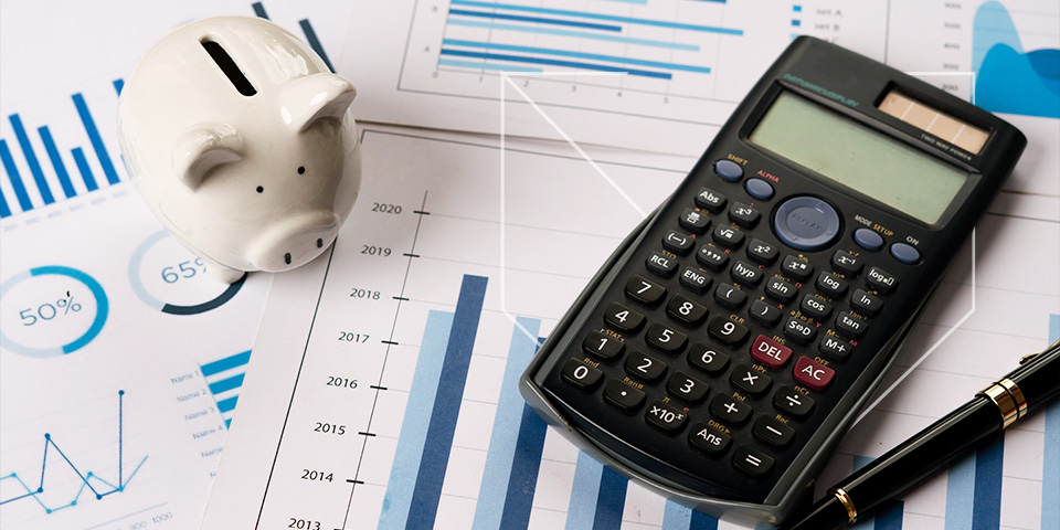 piggy bank and a calculator on top of financial analytical reports