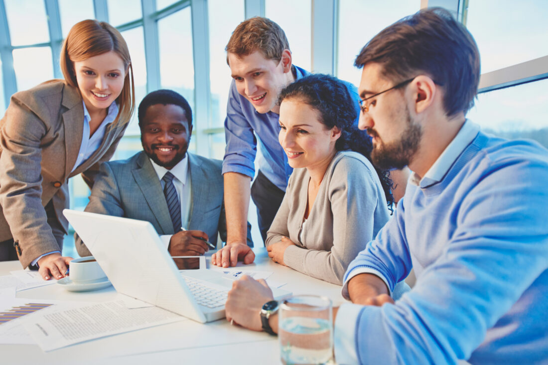 a group of people are looking at a laptop computer discussing tax season