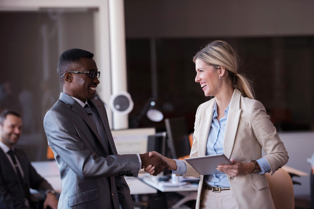 a woman holding a tablet and shaking hands with a man