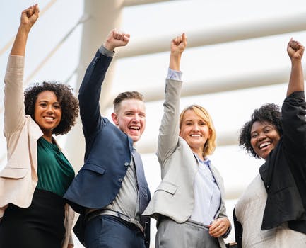 a group of business people are raising their fists in the air and smiling