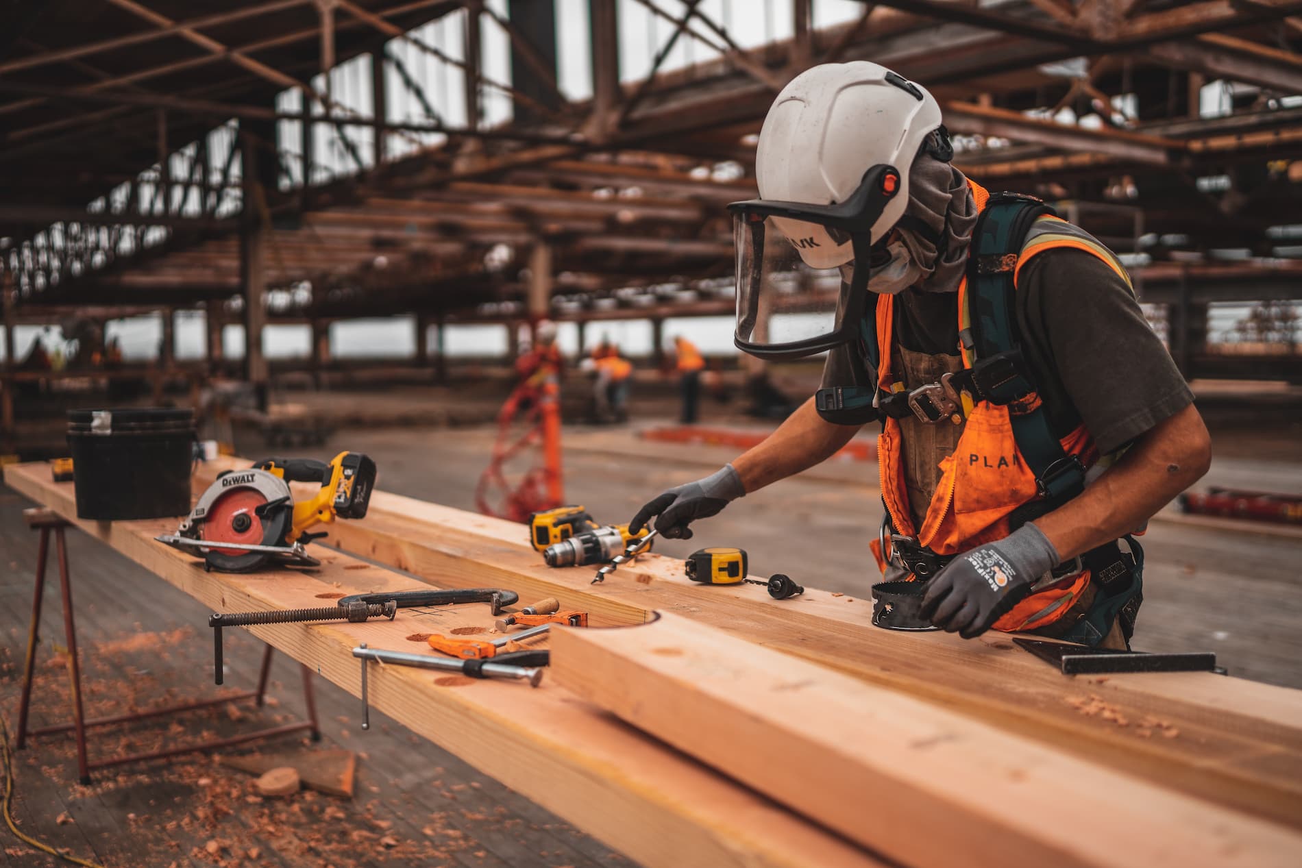 a man wearing a hard hat and safety vest working on a piece of wood