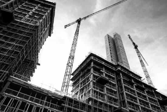 a black and white photo of a building under construction with cranes .