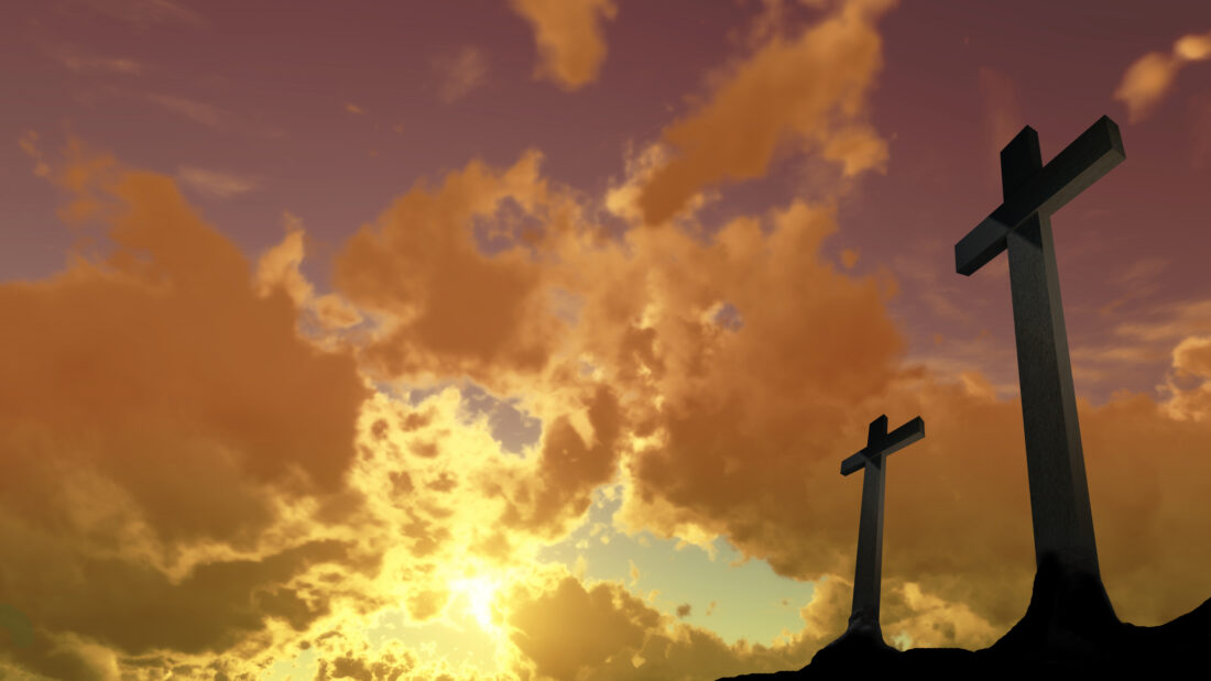 two crosses on a hill with a cloudy sky in the background