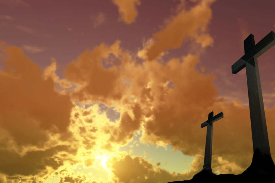 two crosses on a hill with a cloudy sky in the background