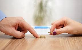 close-up of a man and a woman putting their wedding rings on a wooden table