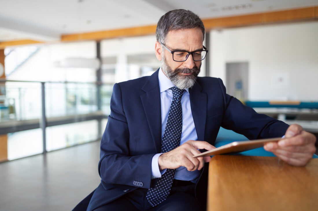 a man in a suit and tie sitting down and using a tablet