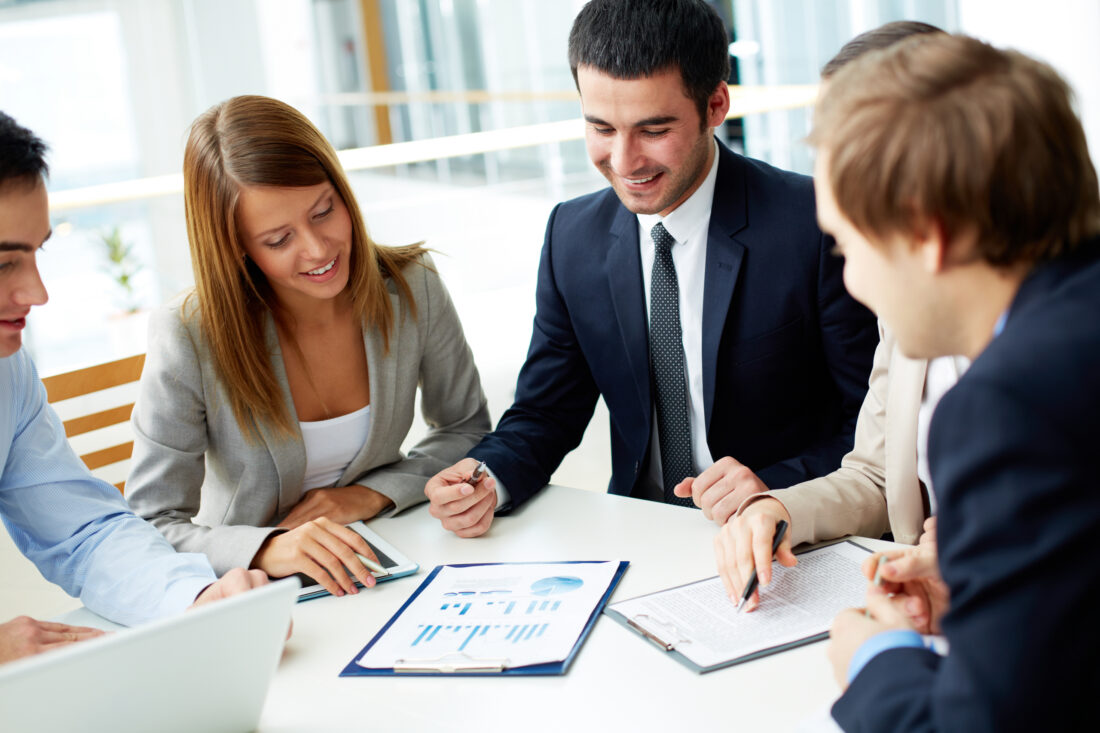 a group of people sitting around a table looking at business documents