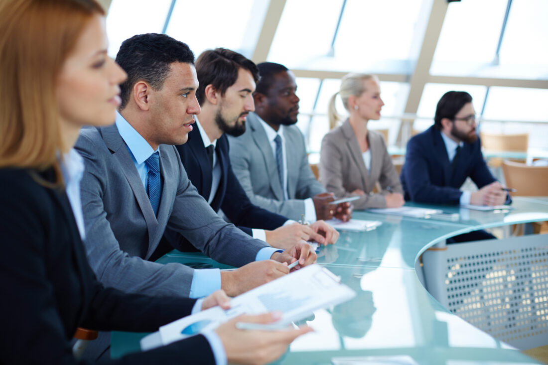 a group of business professionals sitting around a round glass table